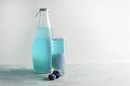One Shot and bottle with blue basil seeds drink with two fresh blueberries on grey textured background. Horizontal, copy space. Minimal concept about healthy beverage, super food. Falooda, sabjaの写真素材