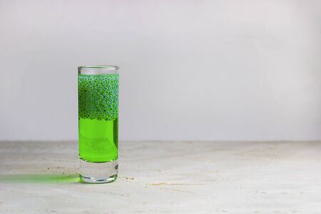 One green shot with basil seeds bright drink on grey textured background with shadow. Horizontal with copy space for text and design. Falooda, sabja. Minimal cpncept about healthy beverage, super foodの写真素材