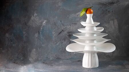 White dishes Pyramid of Christmas tree shape with mandarin with leaf on top, bunch below on dark Creative concept, dishware, veg, agriculture, vegetable, kitchen, restaurant, wallpaper, Xmas, New Yearの写真素材