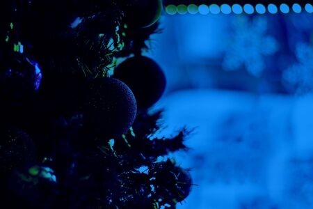 Decorated christmas tree with red balls on background of defocused window with snowflakes and bokeh lights. Hotel and restaurant booking on holidays and party. Classic, blue monochrome, trend 2020の写真素材