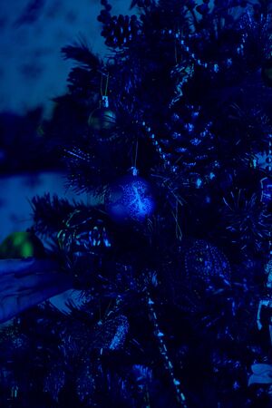 Decorated artificial christmas tree with red balls on background of defocused window with snowflakes and bokeh lights. Vertical. Classic, blue monochrome, trend 2020の写真素材