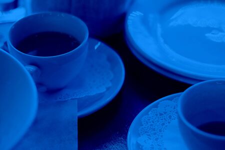 Two tea or coffee cups on wooden table surrounded by dishes, Selective focus. Reastaurant, cafe, breakfast, tableware. Classic, blue monochrome, trend 2020. Horizontal.の写真素材