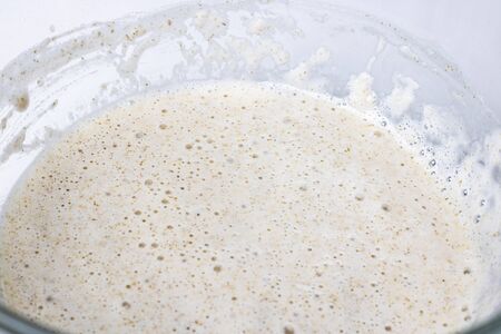 Close up raw sour dough whole wheat pastry for bread, prosess of mixing pre-dough in glass bowl, knead, horizontal with copyspace, selectuve focus, healthy food, nutritious. White background.の写真素材