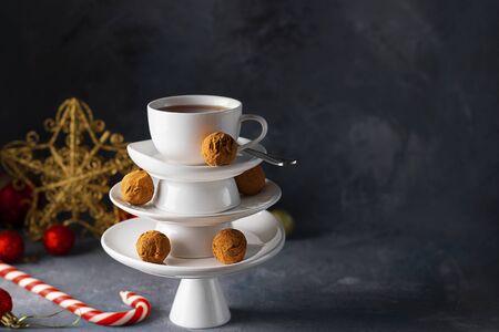 White saucer pyramid with cup of tea on top, like Christmas tree decorated with sweet chocolate truffles, Creative concept, restaurant, postcard, New Year, Xmas, Square, Horizontal with copy spaceの写真素材