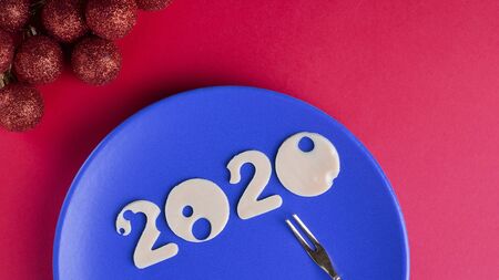 Figures 2020 made of cheese with holes on blue plate with small fork on red background, top view, Horizontal, copy space. Christmas and New year concept for restaurant, Classic, trendの写真素材