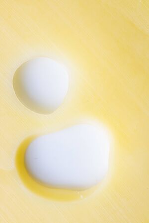 Yellow cheese background with two big holes on white background. Template for design. A piece of delicious cheese. Mouse and rat favorite food. Close up. Vertical.の写真素材