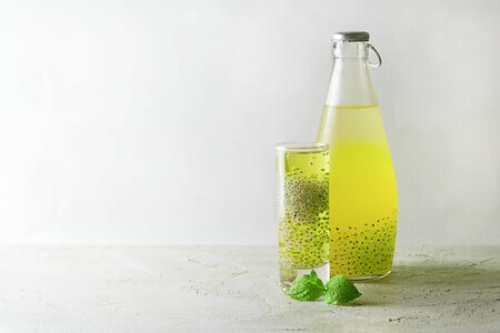 One Shot and bottle with yellow green basil seeds drink with fresh mint leave on grey textured background. Horizontal, copy space. Falooda, sabja. Minimal concept about healthy beverage, super food.の写真素材