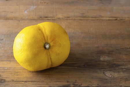 Ugly double organic lemon unusual shape on wooden textured surface with knife. Buying imperfect product to reduce food waste. Yellow bright color fruit. Eco trend. Horizontal. Cookingの写真素材