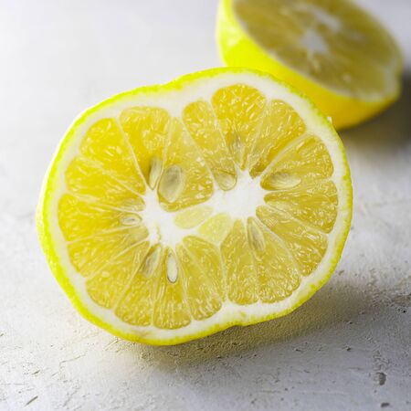 Double organic lemon cut into two pieces with seeds unusual shape on grey background. Buying imperfect products to reduce food waste. Yellow bright color. Eco trend. Square. Ugly fruitの写真素材
