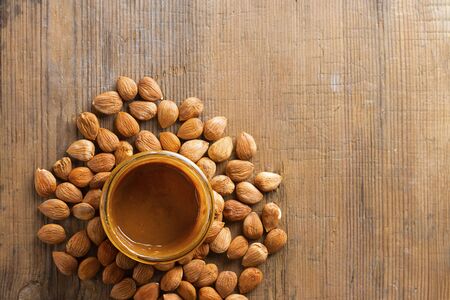 Apricot kernels handful and glass jar with nut butter on wooden background. Food concept with copy space. Top view. Product is good for cardio vascular system, remedy for parasites, full of vitamims.の写真素材