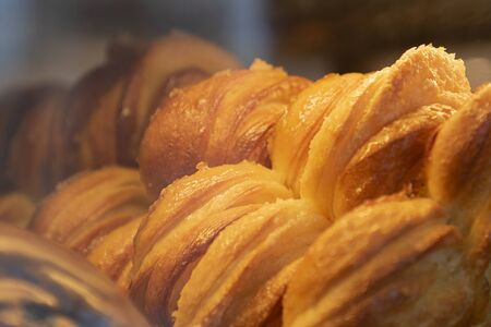 Many Sweet pastry buns on shop window of confectionery. Selective focus. Culinary background for wallpaper of postcard. Horizontal. Close up.の写真素材