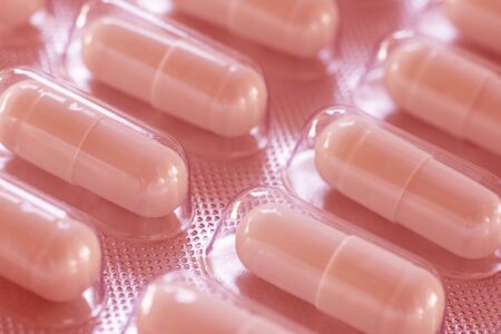 Pack of pills closeup. Diagonal rows of oval tablets. Background or texture about Medicine, Health, Vitamins and food supplement. Horizontal. Red toneの写真素材