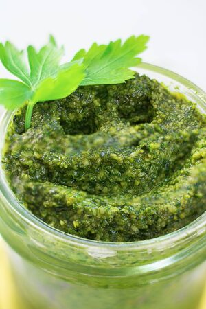 Smile drawn on homemade parsly pesto with cashew nuts in glass jar, decorated with green leaves. Macro, selective focus. Vegan, healthy sauce, italian cuisine. Vertical shot. Positive effect of greensの写真素材