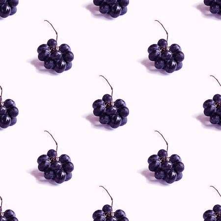 Trendy seamless pattern with small bunch of black round grapes with shadow on blank white. Photographic collage. Creative background. Natural organic fruit. Healthy, Sweet and tasty food. Violet tone.の写真素材