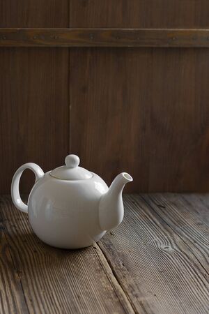 White teapot on old wooden table over green backgroundの写真素材