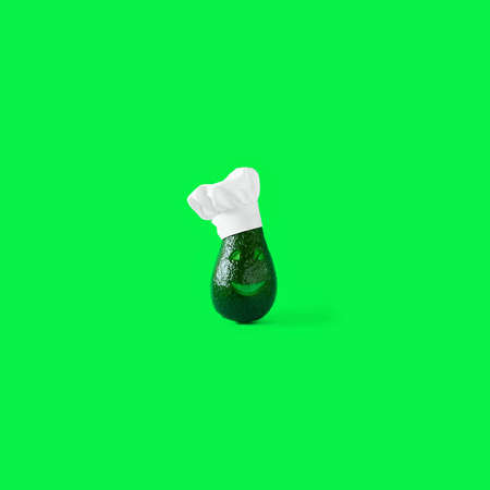 Finny green fresh avocado, with smile and eyes on face wearing clean white restaurant Chefs hat on green chroma key background. Square with copy space. Creative concept for healthy cooking and food.の写真素材