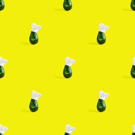 Diagonal rows of green avocado wearing Chefs hat on yellow background. Square with copy space. Creative concept for healthy cooking and food. Seamless pattern, photographic collage,の写真素材