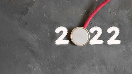 2022 of white drown figures 2 and mockup stethoscope on black chalk board as 0, New Year, Christmas and pandemy concept for professional doctors, medicine, health care istrumets. Top view, copy spaceの写真素材