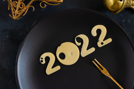 Christmas and New year food concept of 2022. Minimal  for period of time with light cheese snack on fork on plate. Ready picture for postcard with copy space for text and design.の写真素材