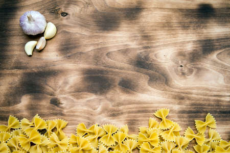 raw Farfalle lie at the bottom of the frame on a wooden table top view with free space at the top of the pictureの写真素材