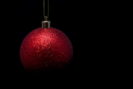 red christmas ball in tense light on black backgroundの写真素材