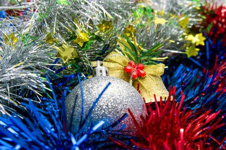 Christmas balls of different colors are on a multicolored tinselの写真素材