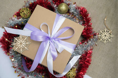 Brown gift box tied with blue ribbon close-up, red tinsel, snowflakes made of wood and Christmas balls of gold colorの写真素材