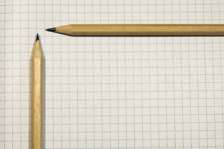 two pencils lie on a piece of paper in a cage, close-up, checkered background