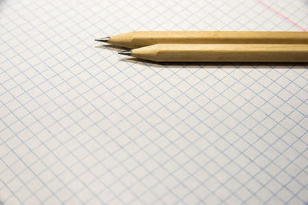 two pencils lie on a piece of paper in a cage, close-up, checkered backgroundの写真素材