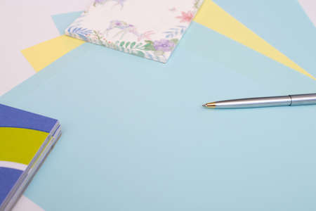 ballpoint pen lies on sheets of blue and yellow paper next to the notebook, white background, layout, Flatleyの写真素材