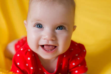 baby, portrait of a little girl with blue eyes closeup, yellow background, red clothesの写真素材