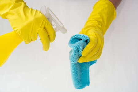 Female hands in yellow rubber gloves hold a spray for cleaning windows and cleaning cloth on a white background. The concept of cleaning the service. Flat lay, Top view. Mock upの写真素材