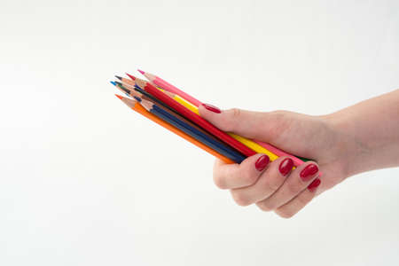 colored pencils in female hand with red manicure, white backgroundの写真素材