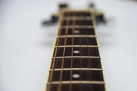 Guitar fretboard close-up top view of the neck of the guitar and strings on white isolated background. Acoustic guitar perspective along fretboardの写真素材