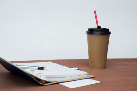 a silver fountain pen, a notebook with a blue cover and a calendar lie on a wooden tableの写真素材