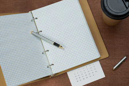 Calendar planner with fountain pen and hot coffee on wood table.office tool.の写真素材