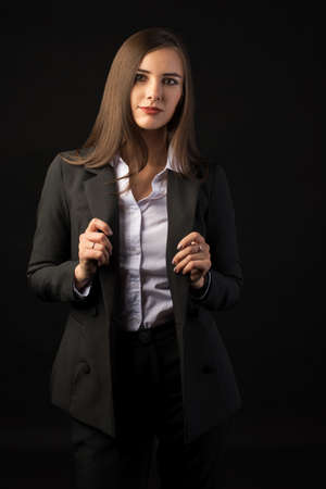 young beautiful brunette girl black background, portrait, straight long dark hair, black jacket, white blouseの写真素材