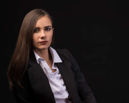young beautiful brunette girl black background, portrait, straight long dark hair, black jacket, white blouseの写真素材