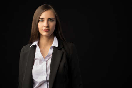 young beautiful brunette girl black background, portrait, straight long dark hair, black jacket, white blouseの写真素材
