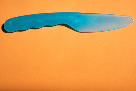plastic knife blue orange background close up top viewの写真素材