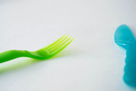 plastic fork green and knife blue white background top view