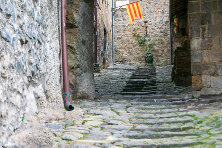 Narrow cobblestone street with stairs and Catalan flag in Bolsena, Italyの写真素材