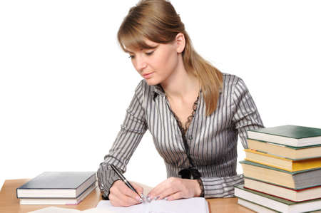 beauty woman with long hair sits at a table with the book and writesの写真素材