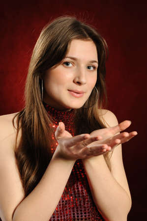  Young woman holding hand presenting a product.On a red backgroundの写真素材