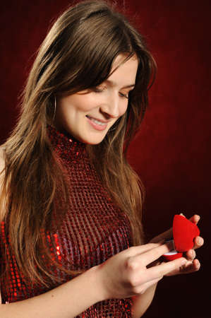Beautiful woman with a heart gift on the red backgroundの写真素材