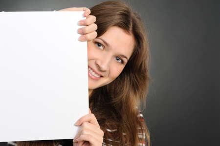 young woman holding empty white board, on a  grey background の写真素材