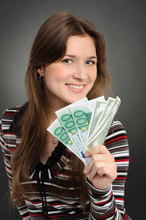 Pretty woman smiling while holding fan made of money  on a  grey background  の写真素材
