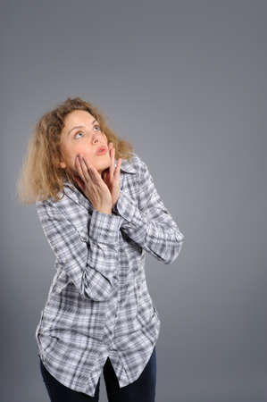 Portrait of a surprised young woman  looking upwards at copyspace against grey background の写真素材