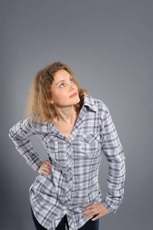 Portrait of a surprised woman  looking upwards at copyspace against grey background の写真素材