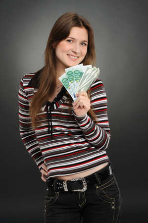 Pretty woman smiling while holding fan made of money  on a  grey background  の写真素材
